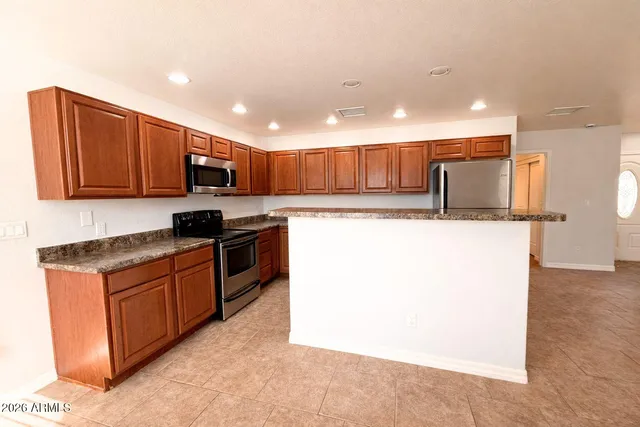 a kitchen with stainless steel appliances granite countertop a stove a sink a refrigerator and a microwave