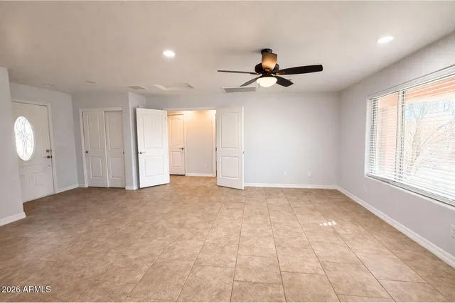 an empty room with windows and fan
