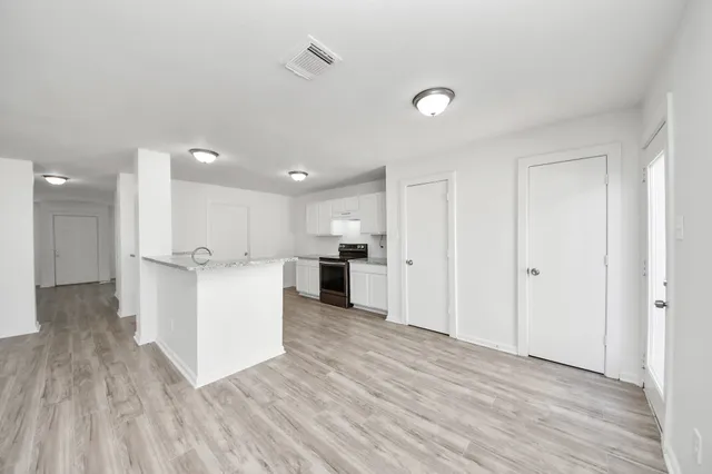 a view of kitchen with kitchen island wooden floors appliances and cabinets