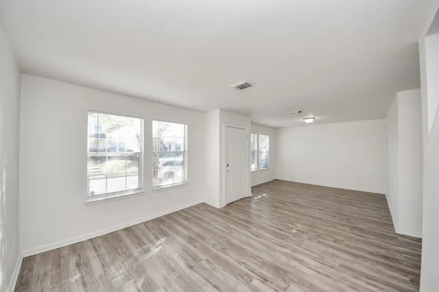 a view of an empty room with wooden floor and window