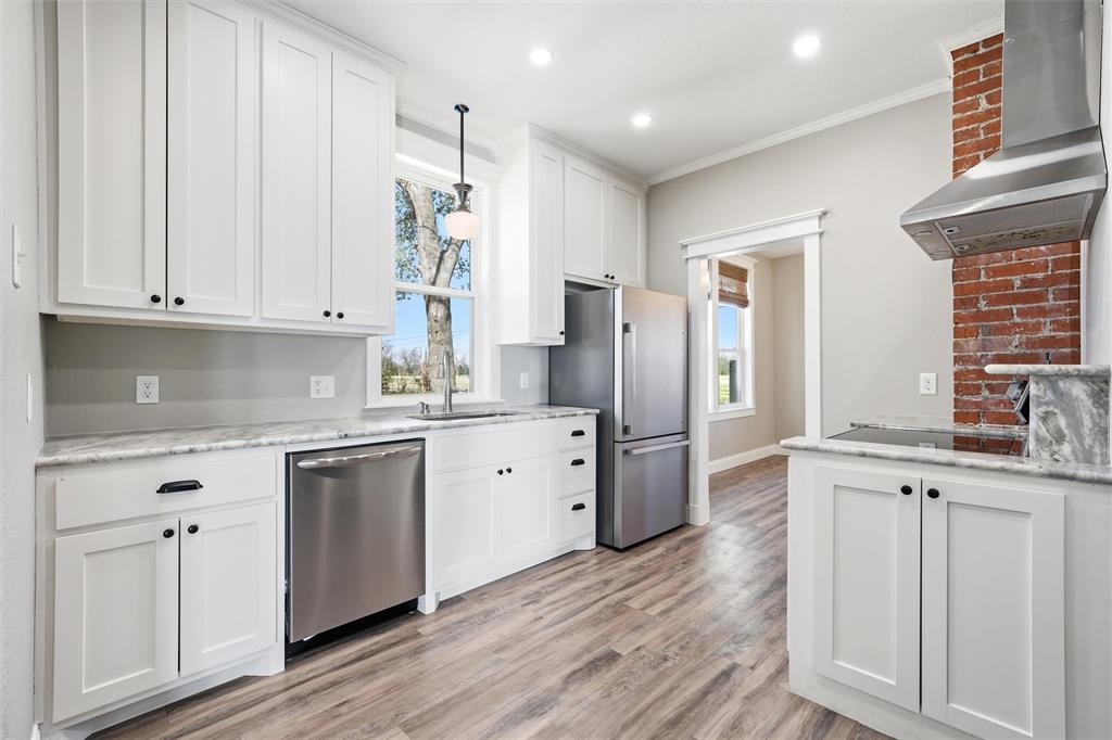 3801 South 4th Street Waco, TX 76706 - Photo 9 of 26 a kitchen with stainless steel appliances granite countertop a refrigerator a sink dishwasher and white cabinets with wooden floor
