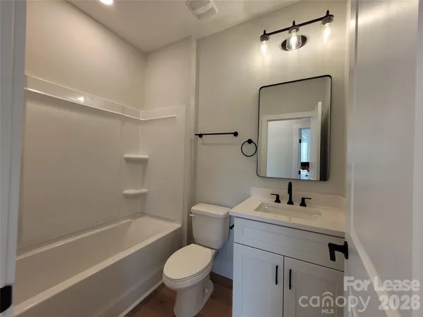 a bathroom with a toilet a sink a mirror a bathtub and vanity