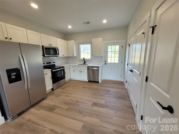 a large kitchen with a stove a refrigerator a sink dishwasher and wooden cabinets