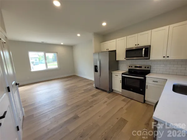 a kitchen with granite countertop a refrigerator a sink a stove a microwave a counter space and cabinets