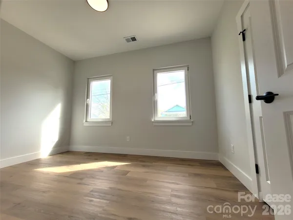 an empty room with wooden floor and windows