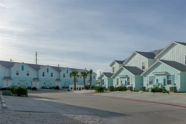 a view of a big house with a street and plants
