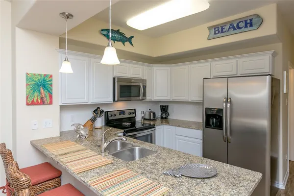 a kitchen with stainless steel appliances granite countertop a sink a stove a refrigerator a washer dryer and a dining table