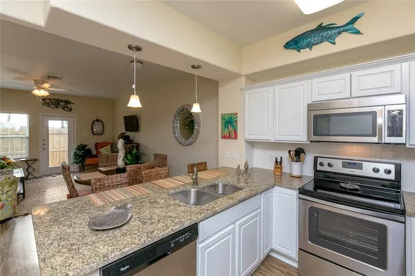a kitchen with granite countertop a sink and a stove top oven with wooden floor