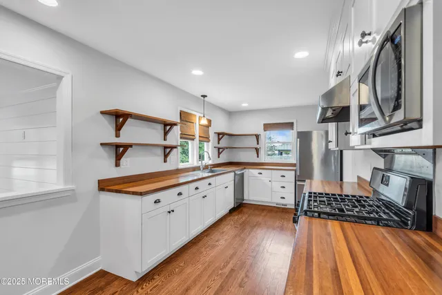 a view of a livingroom with a fireplace a ceiling fan and windows