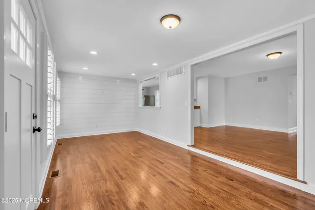 a view of an empty room with window and wooden floor