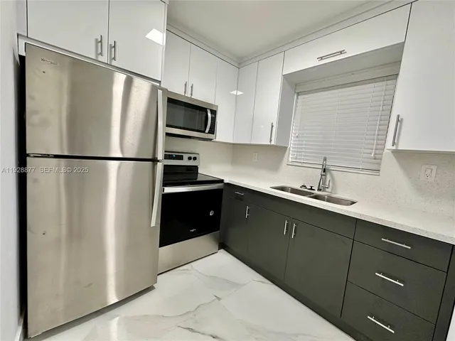 a kitchen with a refrigerator sink and white cabinets