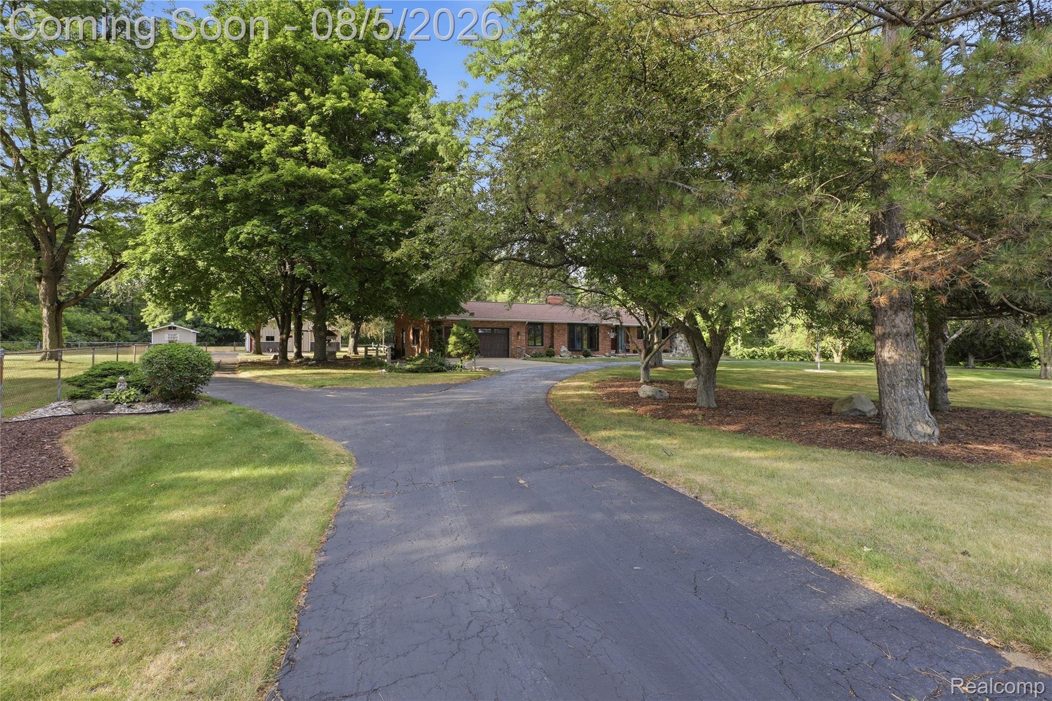 6478 West Stanley Road Mount Morris, MI 48458 - Photo 6 of 80 Expansive asphalt driveway with a branch to a secondary structure, surrounded by mature trees, manicured lawns, and mulched landscaping with natural rock accents