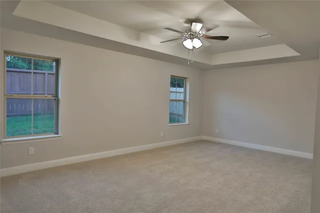an empty room with windows and chandelier fan