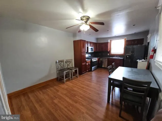 a kitchen with granite countertop stainless steel appliances a refrigerator a stove a sink a window and wooden floor