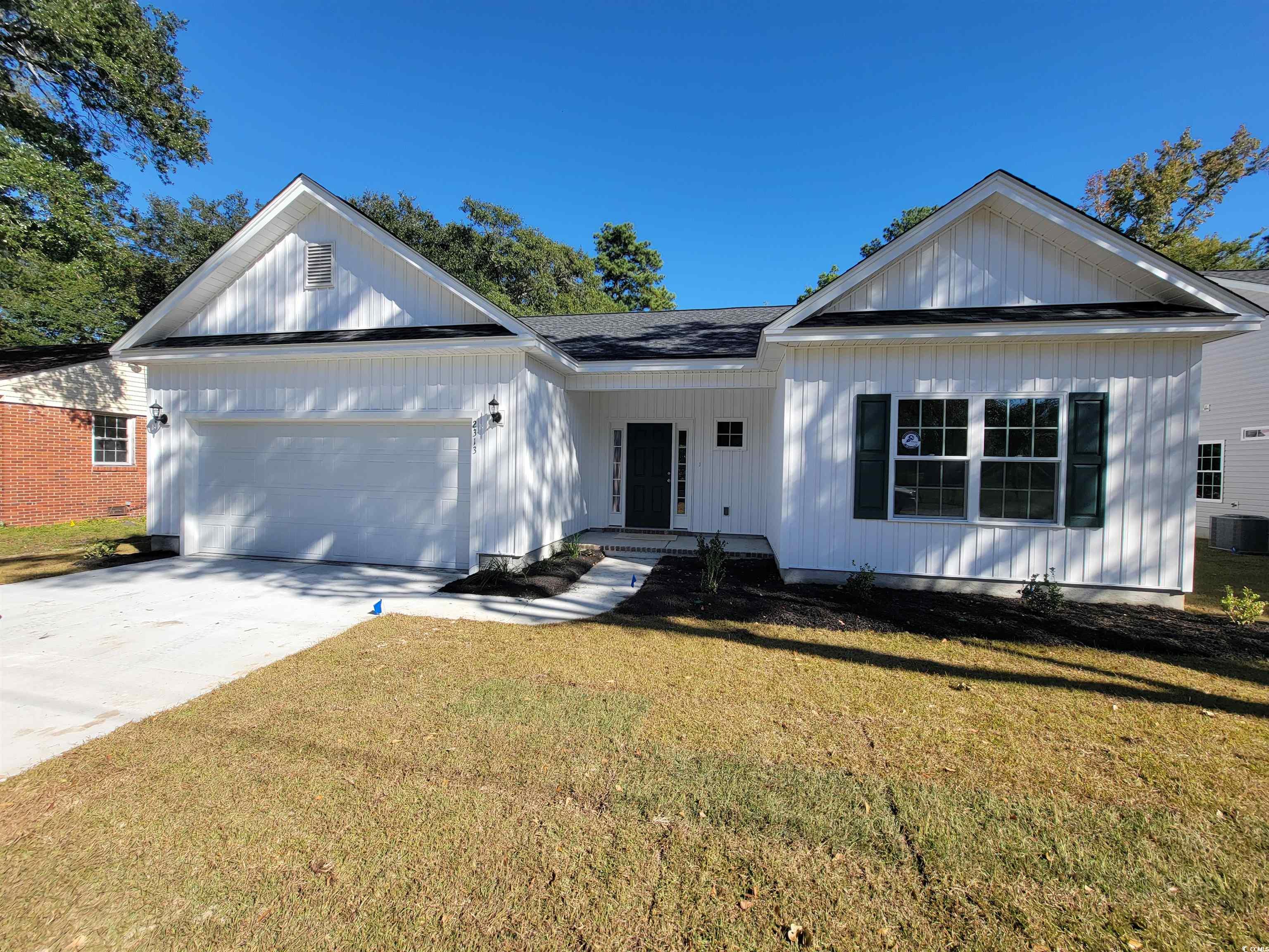 View of front of home with a front yard, driveway, a garage, and a shingled roof
