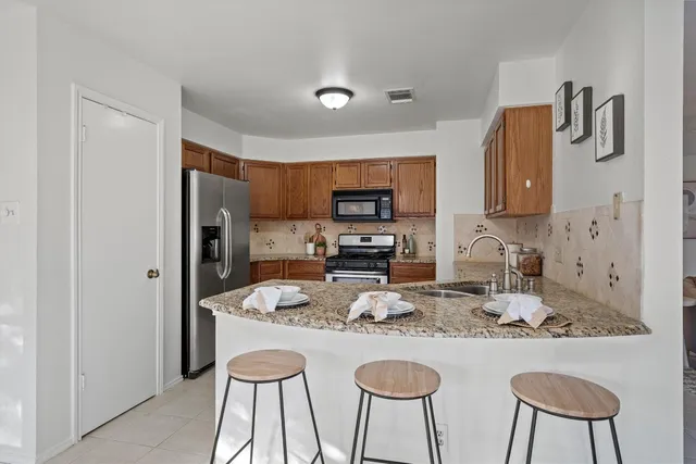 a kitchen with stainless steel appliances granite countertop a refrigerator and a stove top oven