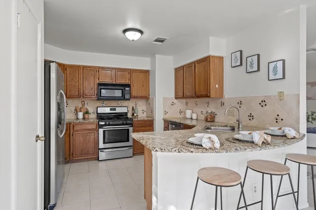 a kitchen with kitchen island granite countertop a sink and stainless steel appliances