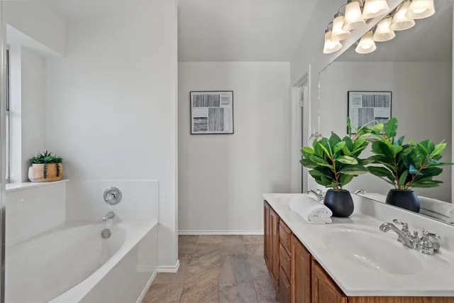 a bathroom with a double vanity sink a tub and a mirror
