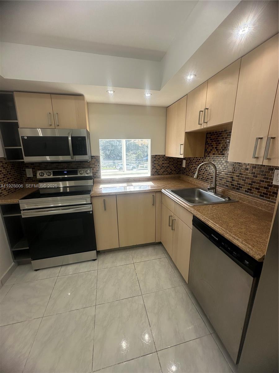 250 180th Drive, Unit 254 Sunny Isles Beach, FL 33160 - Photo 5 of 36 a kitchen with a stove a sink and a microwave