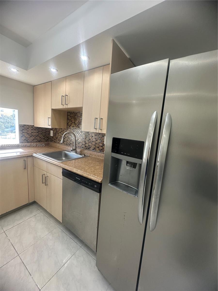 250 180th Drive, Unit 254 Sunny Isles Beach, FL 33160 - Photo 6 of 36 a kitchen with a sink a refrigerator and cabinets