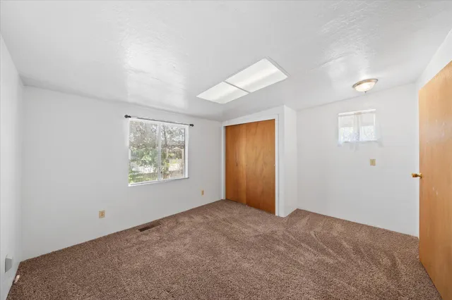 a view of an empty room with window and closet area
