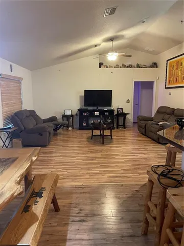 a living room with furniture a flat screen tv and kitchen view
