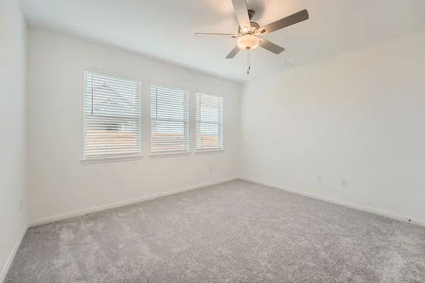 an empty room with chandelier fan and windows