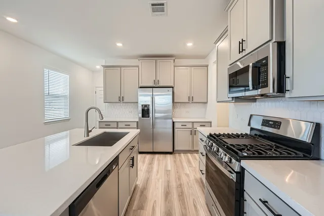 a kitchen with stainless steel appliances granite countertop a sink stove microwave and refrigerator