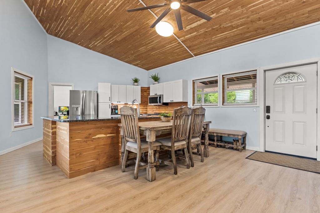 1129 Holly Road Gilmer, TX 75644 - Photo 9 of 31 Open-concept interior featuring light wood-finish flooring, a vaulted wood plank ceiling, and a kitchen island with a dark countertop and wood panel base