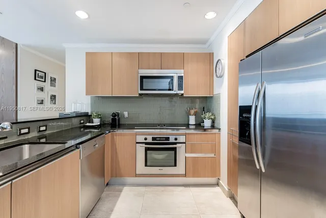a kitchen with stainless steel appliances kitchen island granite countertop a refrigerator and a stove top oven