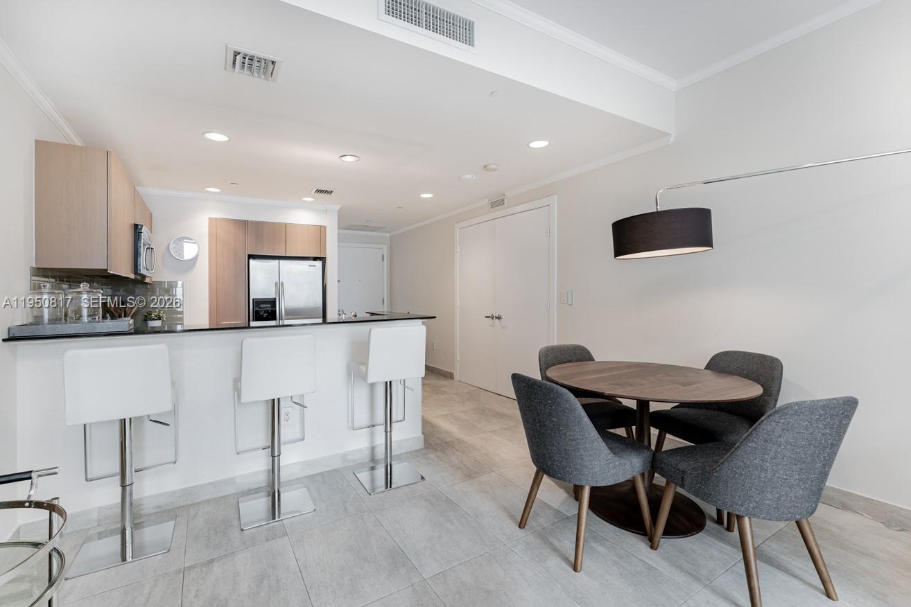 1060 Brickell Avenue, Unit 1507 Miami, FL 33131 - Photo 31 of 56 a kitchen with stainless steel appliances kitchen island granite countertop a dining table chairs and a refrigerator