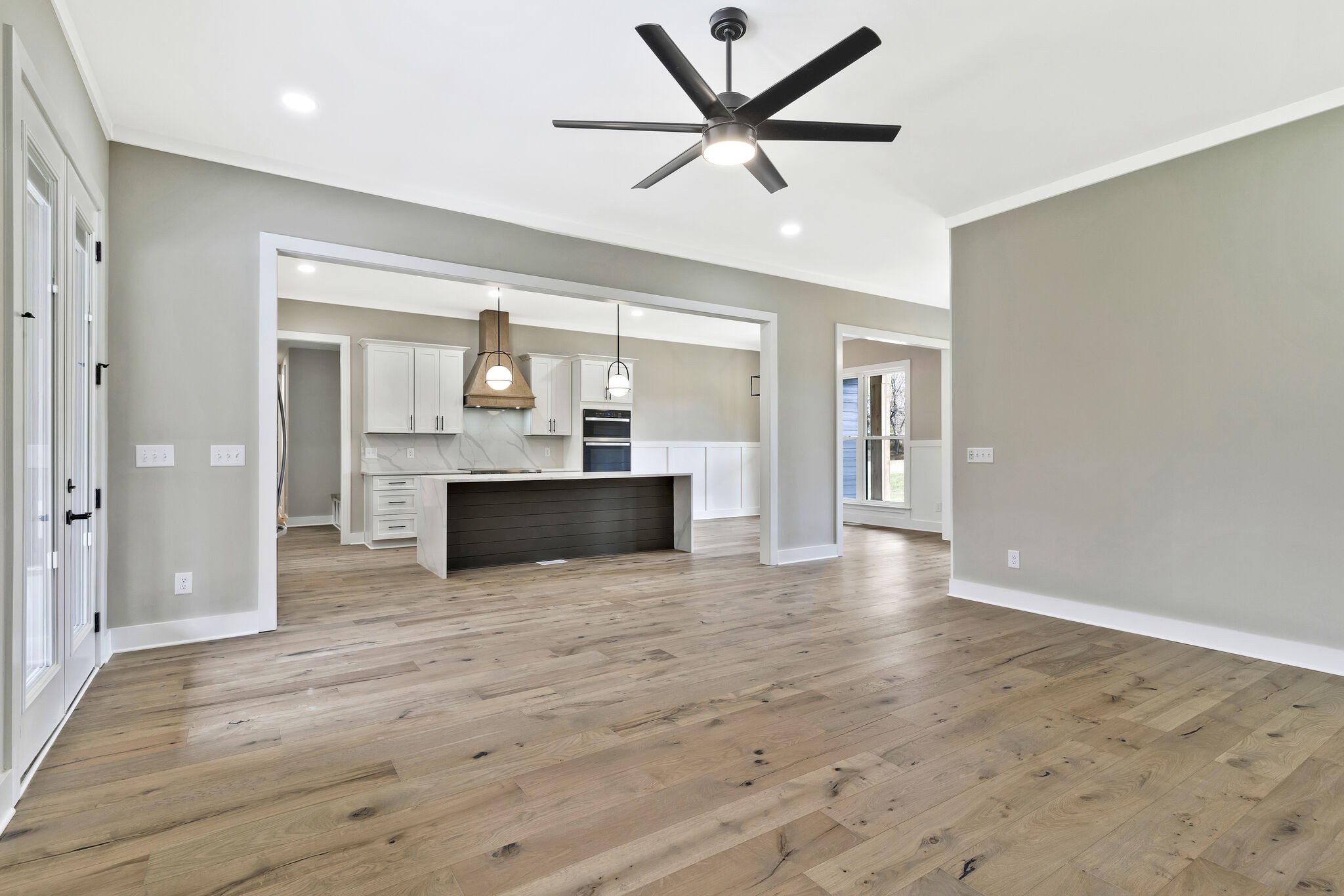3435 Highway 25 Cottontown, TN 37048 - Photo 12 of 52 an empty room with wooden floor a ceiling fan and a kitchen space