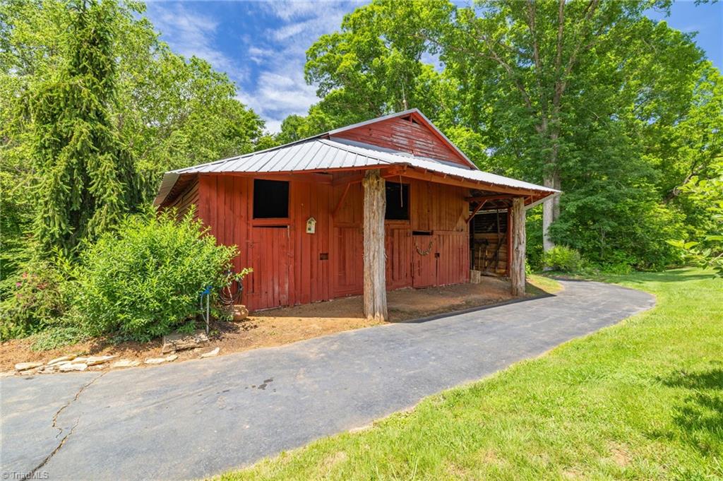 1134 Edwards Farm Road King, NC 27021 - Photo 31 of 50 Who doesn't love a big red barn, complete with metal roof, electrics, workshop, stalls, drive thru detached garage on each end, hayloft , tons of storage and hydraulic water pump for all the wonderful fruit trees and landscaping surrounding the gardening area