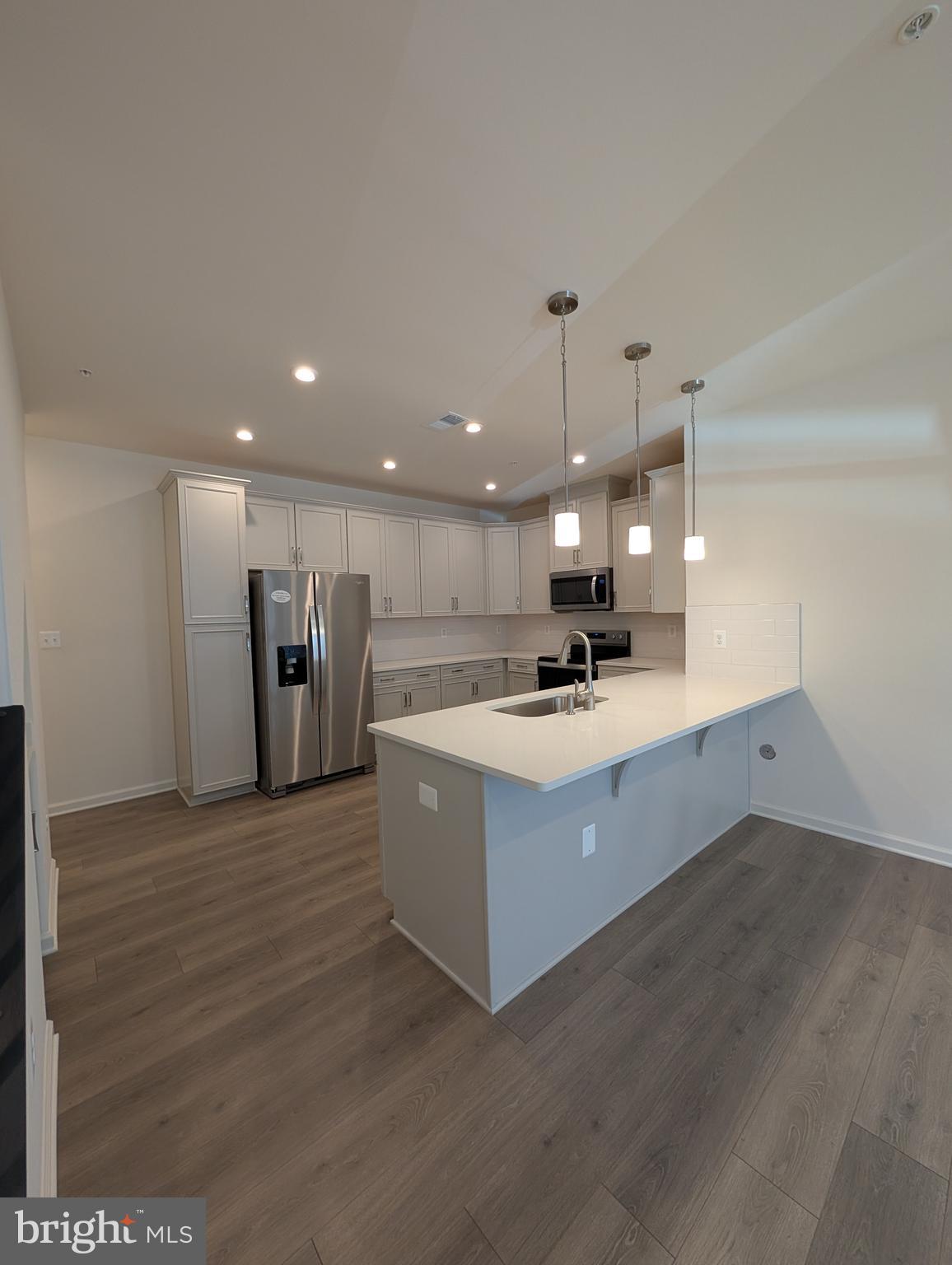 9985 A Justify Run Laurel, MD 20723 - Photo 3 of 33 a large white kitchen with a sink dishwasher a refrigerator and a oven with large countertops