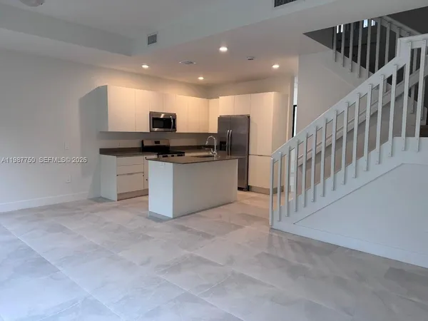 a kitchen with stainless steel appliances kitchen island granite countertop a stove a sink and a refrigerator