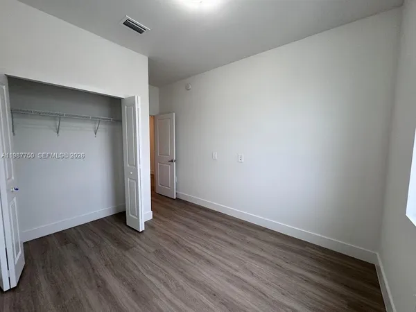 an empty room with wooden floor and closet