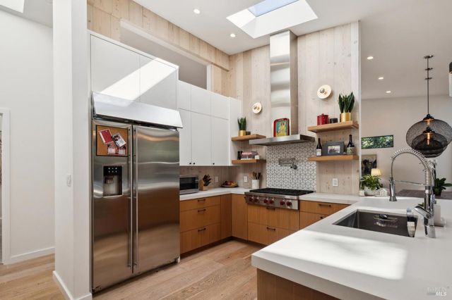 a kitchen with stainless steel appliances granite countertop a stove and a view of living room