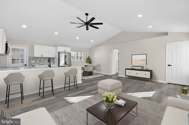 a living room with furniture and kitchen view with wooden floor