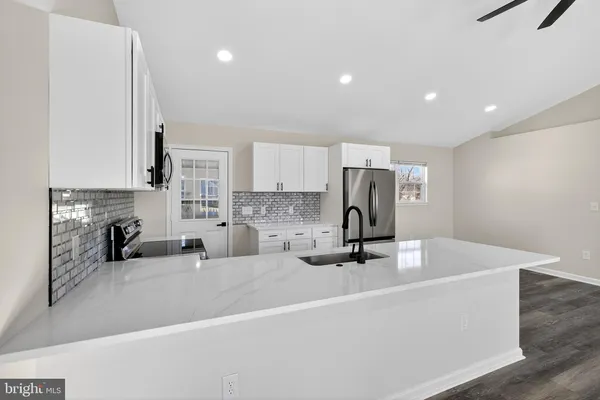 a large kitchen with stainless steel appliances granite countertop a sink a stove and a refrigerator