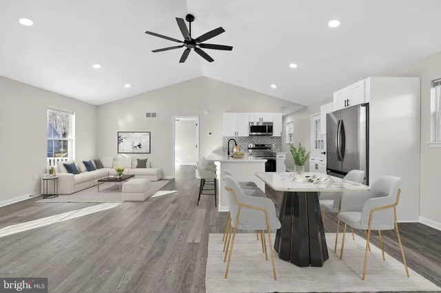 a large white kitchen with stainless steel appliances kitchen island a large counter top and a stove top oven