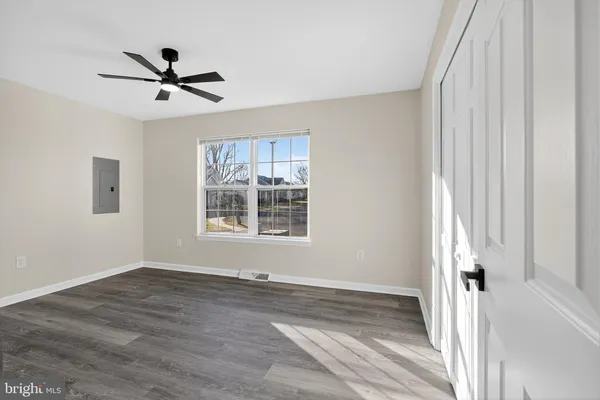 an empty room with wooden floor fan and windows