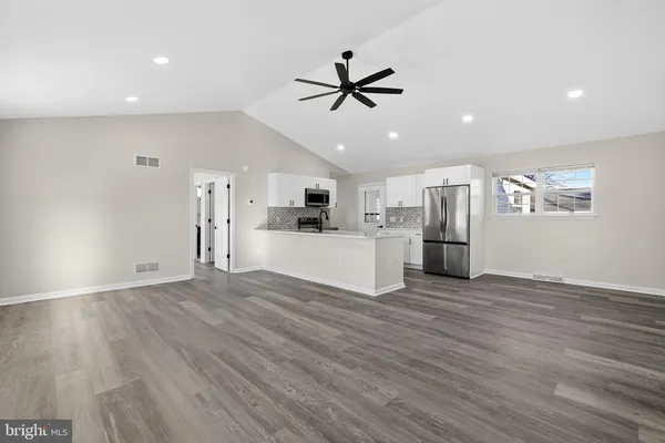 a view of large kitchen with stainless steel appliances refrigerator stove microwave and cabinets