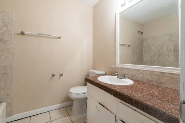 a bathroom with a granite countertop sink a toilet and a mirror