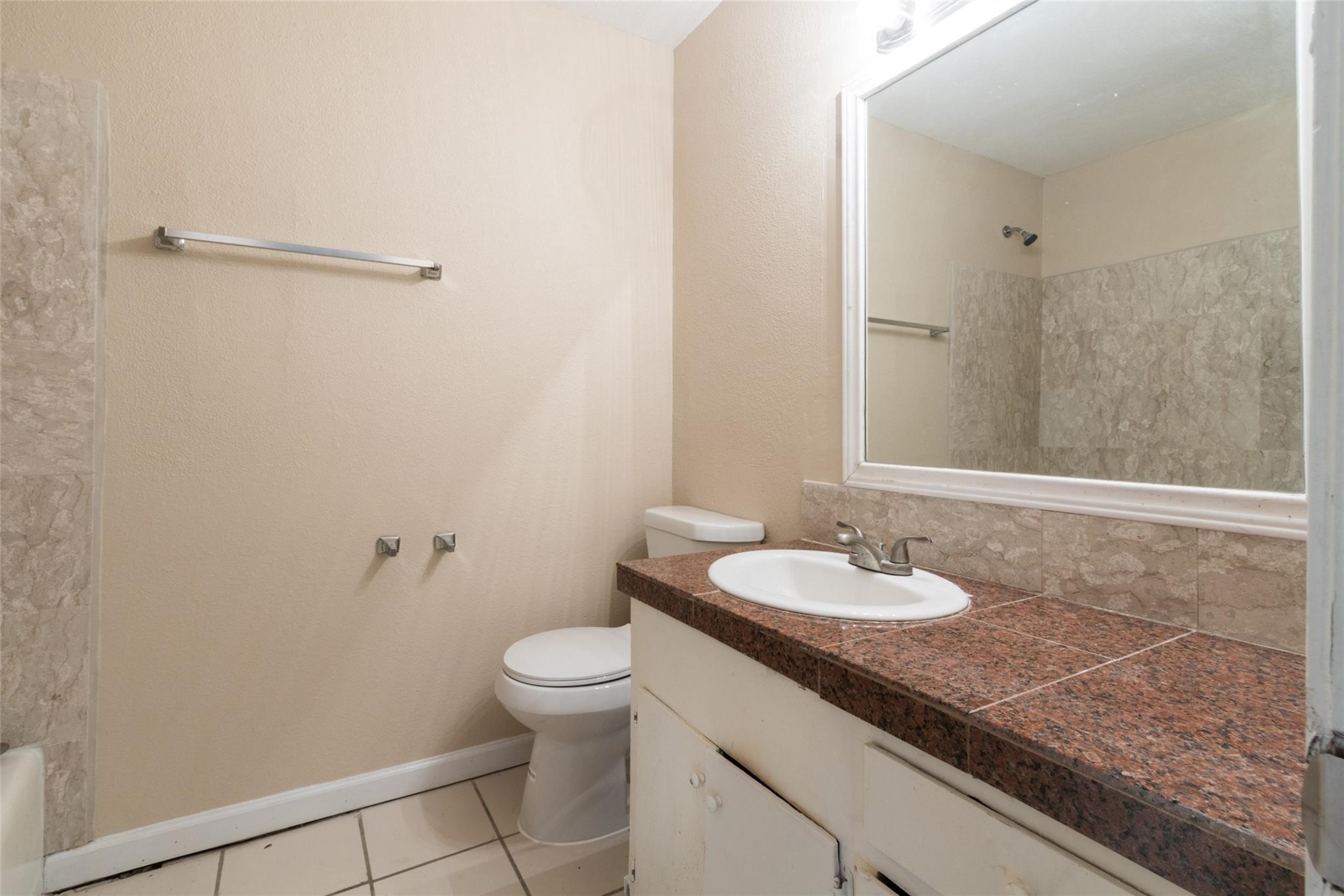 3823 Heatherbrook Drive Houston, TX 77045 - Photo 8 of 11 a bathroom with a granite countertop sink a toilet and a mirror