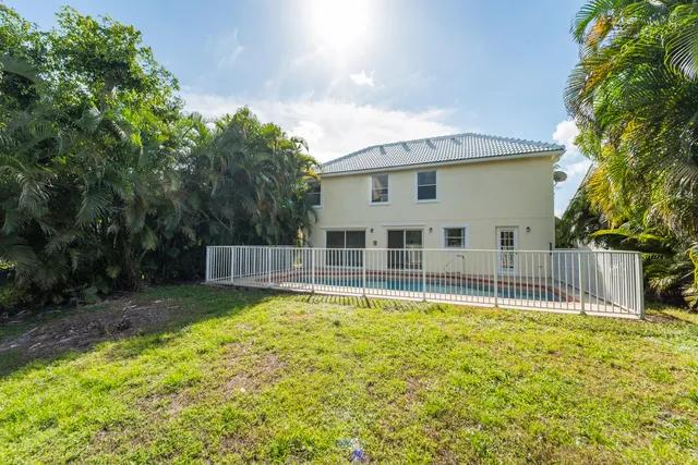 a view of a house with a yard and a large tree