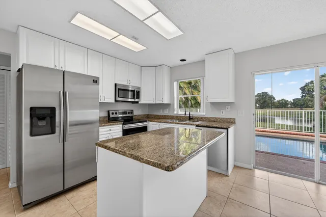 a kitchen with stainless steel appliances granite countertop a refrigerator a sink a stove a microwave and island