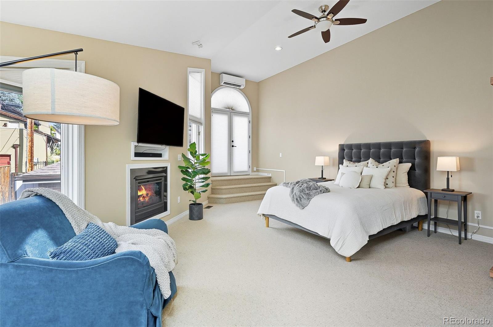 358 Steele Street Denver, CO 80206 - Photo 24 of 48 a spacious bedroom with a bed a couch and a flat tv screen