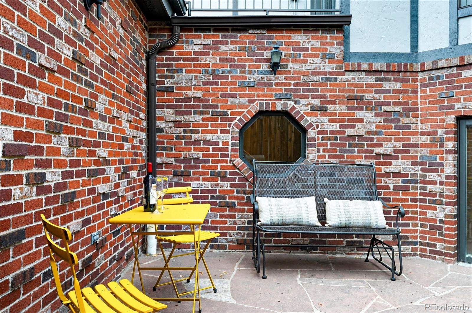 358 Steele Street Denver, CO 80206 - Photo 43 of 48 a brick building with a bench and a potted plant