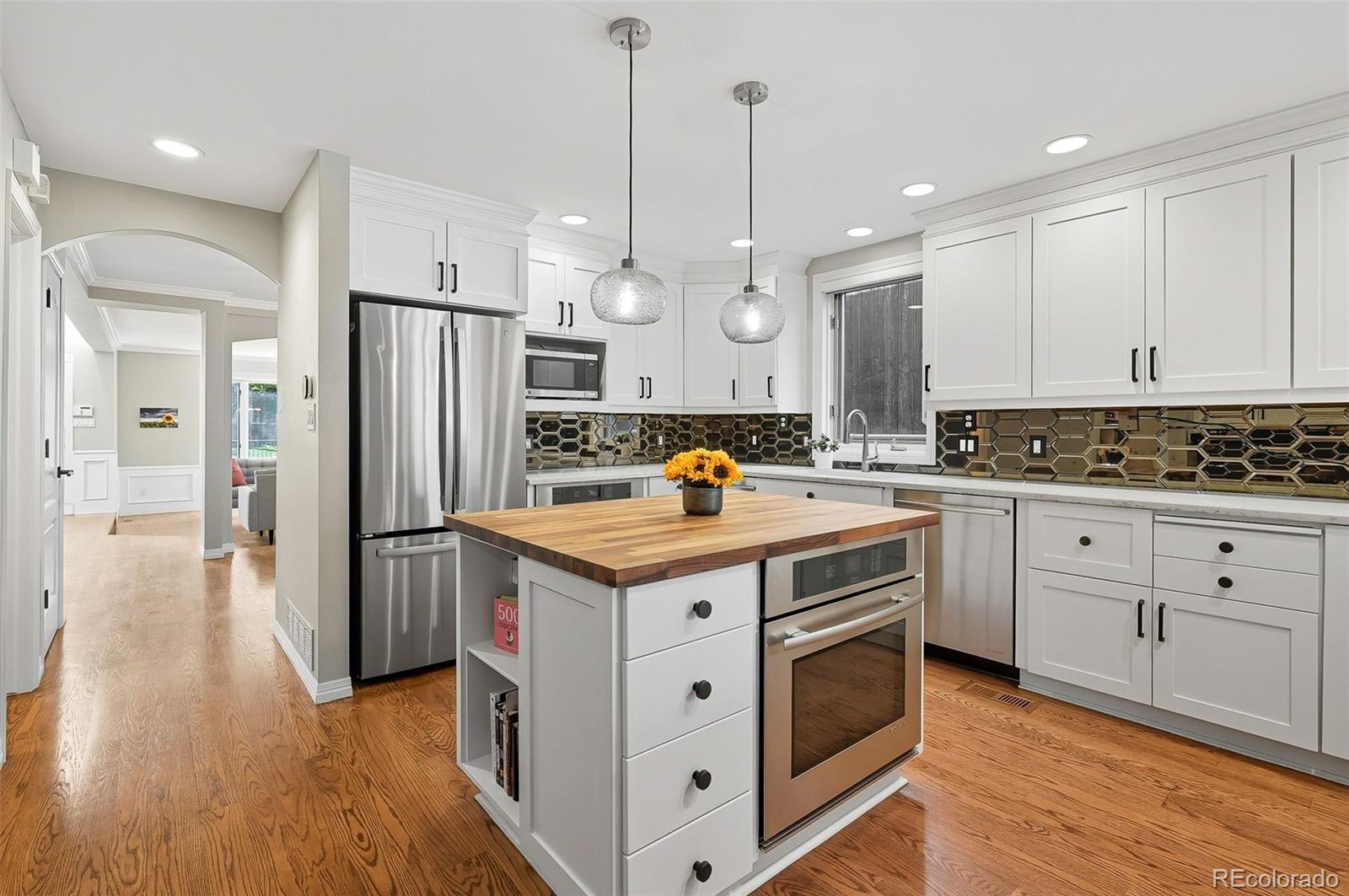 358 Steele Street Denver, CO 80206 - Photo 5 of 48 a kitchen with stainless steel appliances a stove a refrigerator a oven and white cabinets with wooden floor