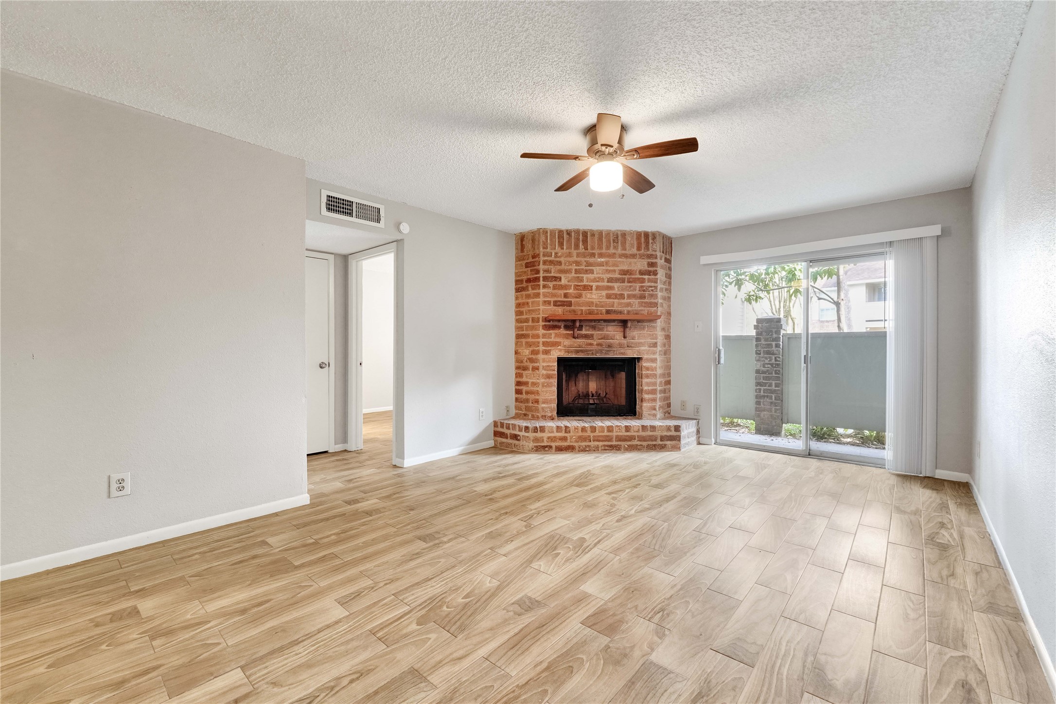 a view of an empty room with a window and a fireplace